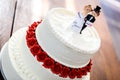 White wedding cake with bride and groom figurines on top Royalty Free Stock Photo